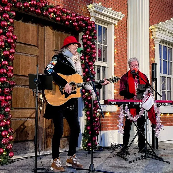 Live musicians performing holiday music in front of a festive Christmas display.